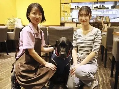 ワンぽてぃとの店内で女性スタッフ（小栗加奈）と娘、大型の黒い犬（オリバー）が並んで座っている様子