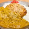 さつまいもカレー、ライス、ポテトバーグが乗った皿の写真。カレーは黄色く、ポテトバーグは焼き目がついて香ばしそう。皿の端には福神漬けが添えられている。