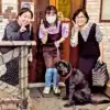 店の入り口前で笑顔でピースサインをする女性３人と、座っている黒いラブラドールレトリバー。