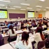 金城学院大学の教壇でマイクを持って講演する講師の小栗加奈。