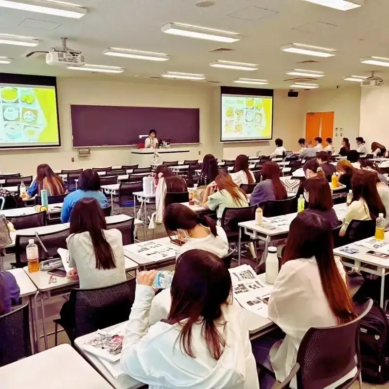 金城学院大学の教壇でマイクを持って講演する講師の小栗加奈。