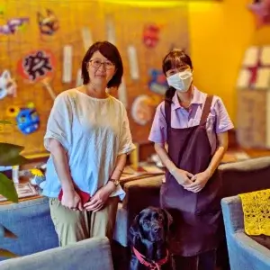 雑誌取材の様子。テーブルを挟んで二人の女性が対話し、足元には看板犬がくつろいでいる。