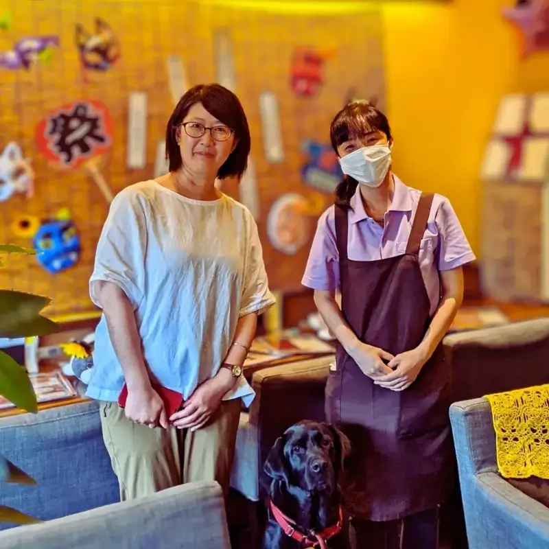 雑誌取材の様子。テーブルを挟んで二人の女性が対話し、足元には看板犬がくつろいでいる。