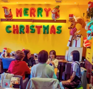 第5回ワン's ペアレンツの交流の様子。クリスマスデコレーションが施されたカフェで、テーブルを囲んで話す5人の女性たち。