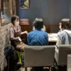 春日井市のカフェレストラン「ワンぽてぃと」で開催された第1回HANASOU-ZEの様子。主催者の女性と看板犬の黒ラブ、そして2名の若者がテーブルを囲み、和やかに話し合っている。