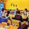 ワンぽてぃとの店内で開催された第4回HANASOU-ZEの様子。主催者の女性と、顔をぼかした一名を含む3名の若者がテーブルを囲み、真剣な表情で語り合っている。