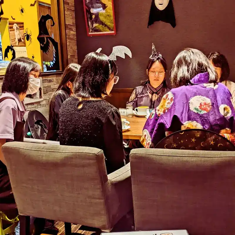 ハロウィンの飾り付けがされたワンぽてぃと店内で、主催者と仮装した若者たちがテーブルを囲み、和やかに話し合っている第5回HANASOU-ZEの様子。
