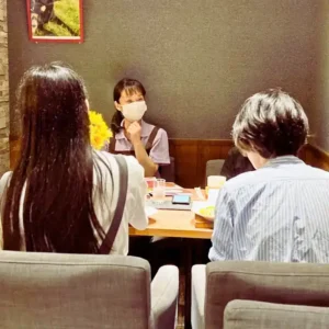 春日井市の「ワンぽてぃと」で、オーナーがHANASOU-ZEの参加者である若い男女の話を真剣に聞いている様子。安心して話せるコミュニケーションの場を象徴する一枚。