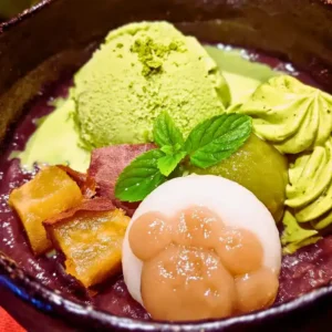 ワンぽてぃとの抹茶ぜんざい。抹茶アイス、抹茶クリーム、蜜いも、ミントの葉、そして中央には肉球の形をした白玉が添えられている。