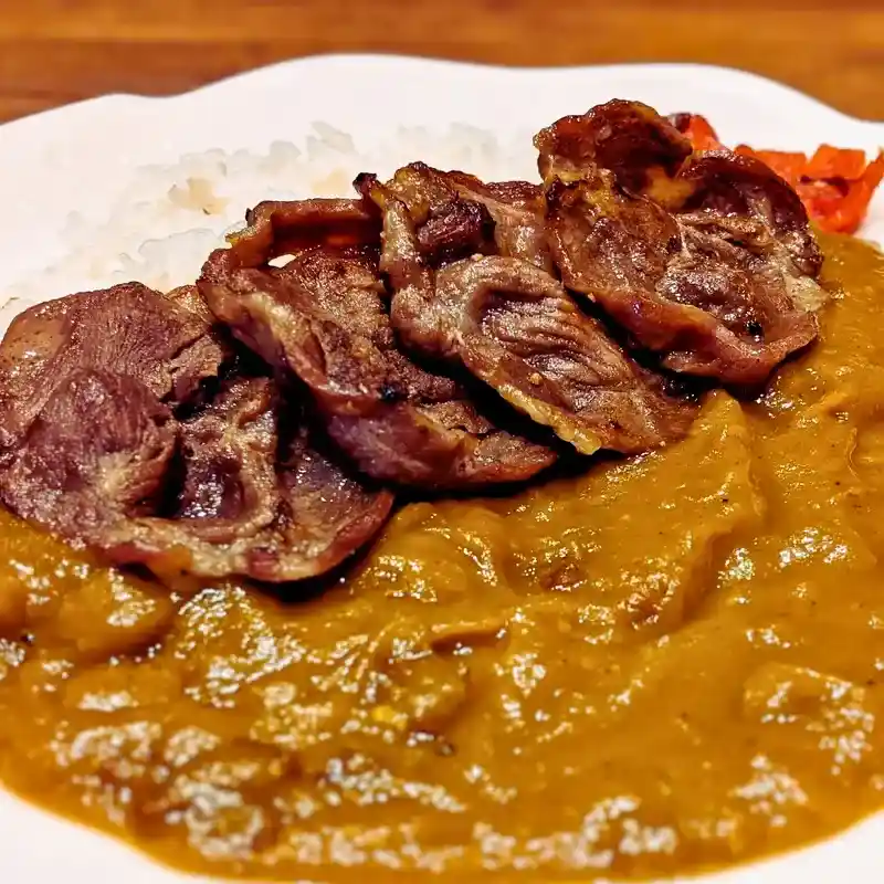 春日井のカフェ「ワンぽてぃと」で提供される牛タンカレーのアップ写真。さつまいもベースのカレーソースの上に、香ばしく焼かれた牛タンが5枚乗っており、食欲をそそる。
