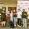 15分雇用（超フレックスタイム制）を体験した後、スタッフ（小栗加奈）と7人の体験者と1匹の黒い犬（オリバー）が建物の前で笑顔でポーズを取っている集合写真