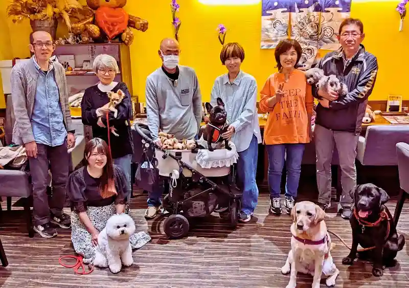 第8回わちゃわちゃの会に参加した犬と飼い主たちの記念写真。ベビーカーに乗ったフレンチブルドッグのパピーを囲み、参加者たちが笑顔でポーズをとっている。