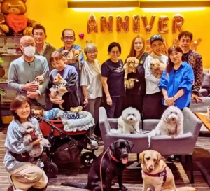 第9回わちゃわちゃの会に参加した犬と飼-い主たちの記念写真。「ANNIVERSARY」の風船が飾られた店内で、初参加の犬も安心して過ごしている様子がわかる。