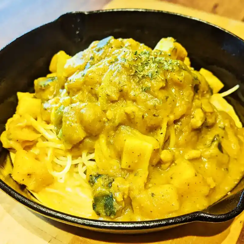 黒いスキレットに盛られたHALLOWEENパスタ。かぼちゃがゴロゴロ入った黄色の濃厚なソースがパスタにかかっている。