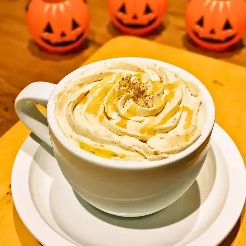 白いカップに入ったパンプキンオレ。ホイップクリームとキャラメルソースが渦巻き状にかかっている。