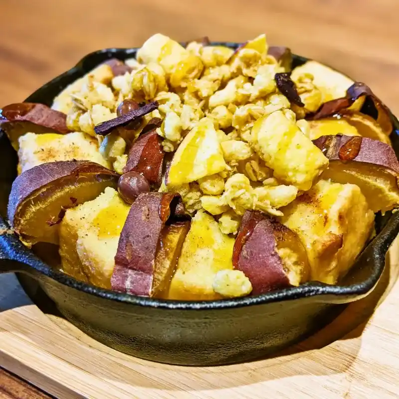 黒いスキレット（小さなフライパン）に入ったパンプキンパンプティング。さつまいも、グラノーラ、豆がトッピングされている。