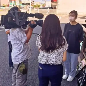 中京テレビ『キャッチ』の取材で、ワンぽてぃとの小栗加奈の娘が「15分雇用によるひきこもり支援」について話す様子。カメラやマイクが設置されている。