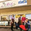 チャンカワイさんとワンぽてぃとオーナー小栗加奈、春日丘高校の生徒たち。店舗前でのテレビ取材記念撮影。