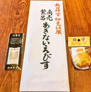 2022年1月、春日井市のカフェ「ワンぽてぃと」にて撮影。娘が熱田神宮の初えびすで授かってきた商売繁盛の福熊手と3体のお札。