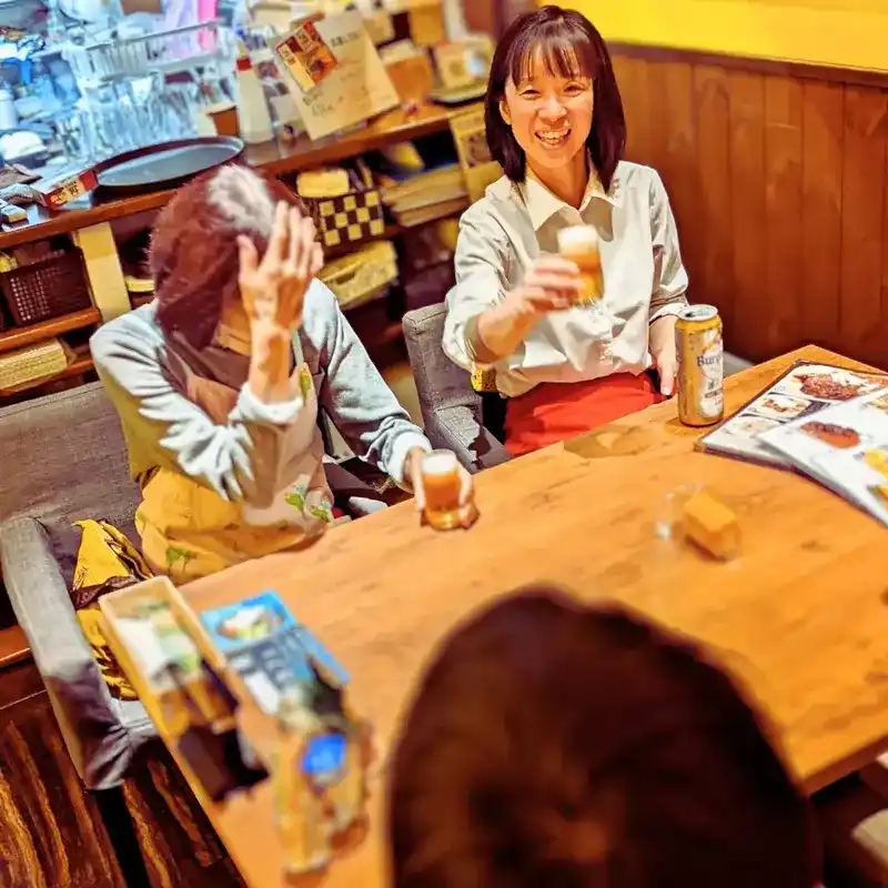 ワンぽてぃとの店内で、笑顔でグラスを合わせて乾杯している女性オーナーとスタッフ。楽しい食事の風景。