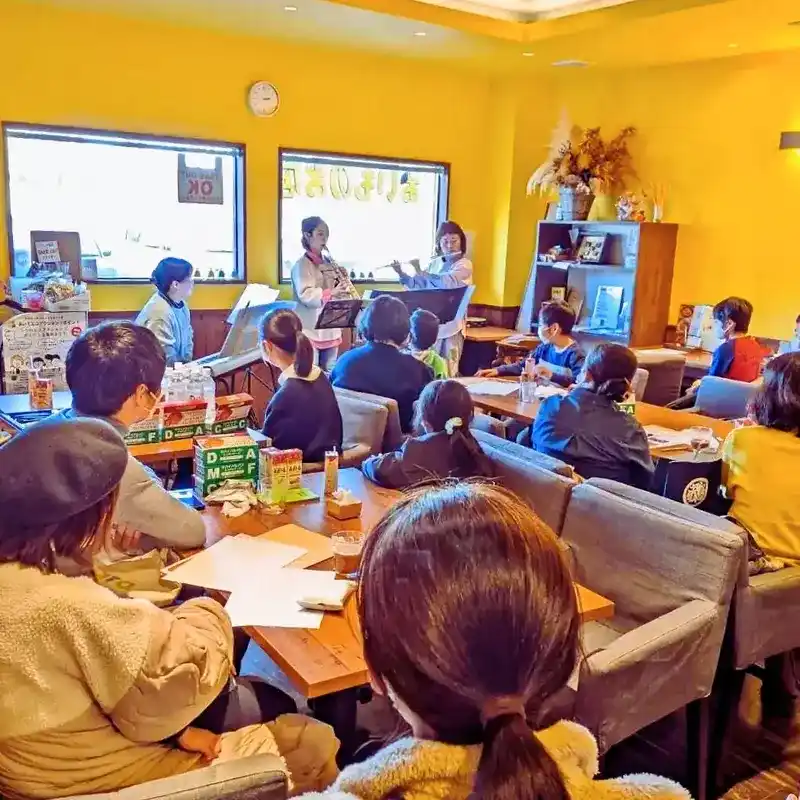 フルートとサックスの演奏を聴き入る参加者の様子。温かい雰囲気の店内。