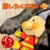 アンパンマンのぬいぐるみを前足で大事そうに抱え込む黒犬。「離したくはない」という文字と「ワンぽてと おいもスイーツカフェ」のロゴが配置されている。