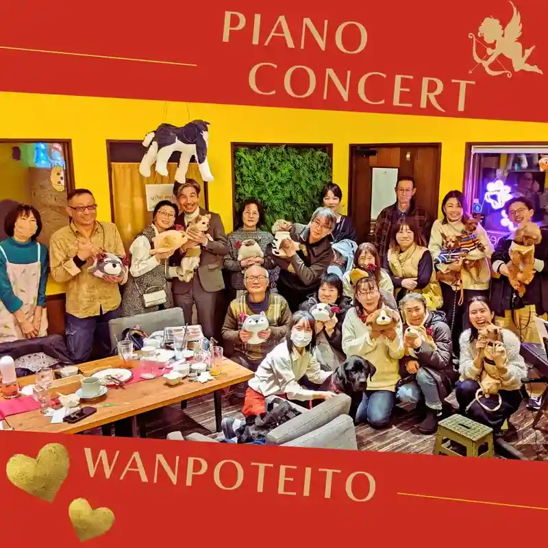 カフェレストラン「ワンぽてぃと」で開催されたピアノコンサートで、参加者とわんちゃんたちが笑顔で並んでいる集合写真。