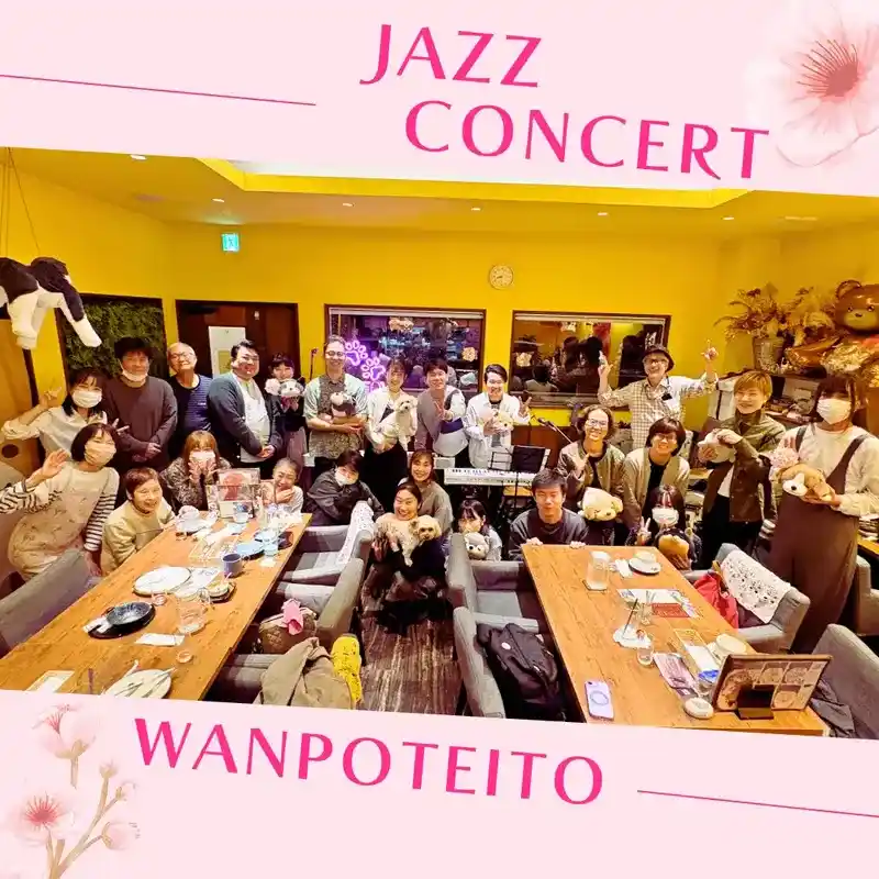 春日井市のカフェレストラン「ワンぽてぃと」で開催された3月のサウンドフェスティバル（生演奏ライブ）終了後の集合写真。サックスやフルートを持った演者様、お客様、ワンちゃんたちが笑顔で写っています。
