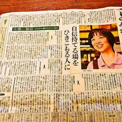 「自信持てる場を ひきこもる人に」という見出しと、笑顔の小栗加奈さんの写真が掲載された新聞の切り抜き記事。15分から働けるカフェ運営について紹介されている。