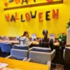 ハロウィン仕様に飾られた黄色い壁のカフェレストラン「ワンぽてぃと」のカウンター席で、並んで作業をするエプロン姿の2名のスタッフ。