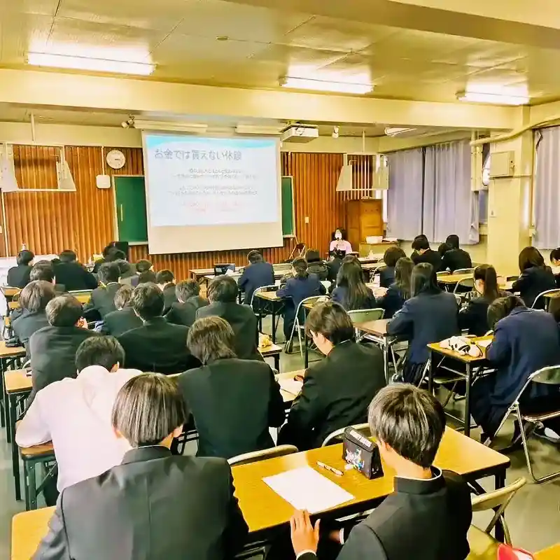 満員の名古屋北高校の教室で、カフェ「ワンぽてぃと」オーナーの小栗加奈による15分雇用や不登校・ひきこもり支援(とまり木事業)の講演に真剣に耳を傾け、メモを取る高校生たちの後ろ姿