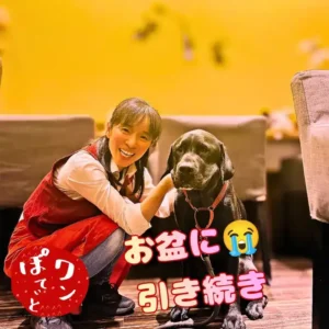 笑顔で寄り添う「ワンぽてぃと」オーナーの小栗加奈と看板犬のオリバー（黒い犬）。画像にはお店の赤いロゴと、「お盆に引き続き」というテキストが配置されています。